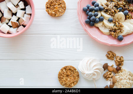 Délicieux en-cas sains sur table en bois blanc, copie de l'espace pour le texte. Des morceaux de fruit dans les plaques de couleur corail naturel, avec les cookies et les écrous de l'avoine. Banque D'Images