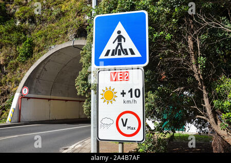 La signalisation routière à Madère, au Portugal. Blue zebra crossing sign. Limite de vitesse blanc signe. La limitation de vitesse est fonction de la météo, en cas de ciel dégagé, la limite est de plus 10 km/h que celui indiqué sur l'enseigne. Banque D'Images