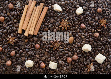 Les grains de café de fond avec différentes épices : anis étoile et des bâtons de cannelle. Noisettes et amandes. Concept de Noël. Banque D'Images