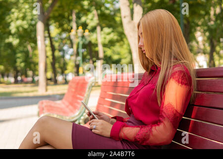 Femme utilise un smartphone dans le parc Banque D'Images