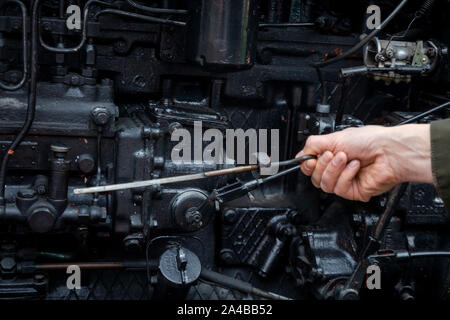 Un homme vérifie un niveau d'huile dans le moteur de tracteur Caterpillar russe T-74 à Moscou, Russie Banque D'Images