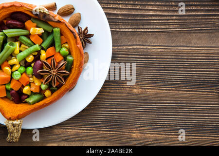 Citrouille farcie : légume savoureux, carottes, haricots, maïs sucré avec des épices, l'anis étoile, la cannelle et les amandes, noix. Close up, vue du dessus, copiez l'espace. Banque D'Images