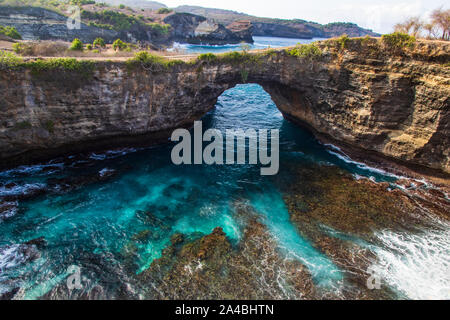 Broken Beach, sur l'île de Nusa Penida, Indonésie. Lagoon en premier plan avec les roches et eau turquoise ; côte sauvage au loin. Banque D'Images