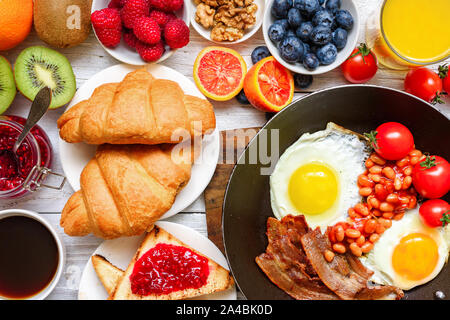 Buffet petit-déjeuner continental complet avec les œufs, bacon, fruits, pain grillé, croissants, fruits, café et jus d'orange . Vue du dessus Banque D'Images