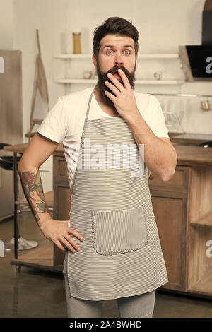 Étant complètement à perte. Surpris cook couvrant sa bouche ouverte avec la main. Homme barbu portant un tablier cuisinier dans la cuisine. Cuire sur son lieu de travail. Aller à cuisiner quelque chose de spécial. Banque D'Images