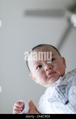 Mignon bébé peu élevé dans l'air à une chambre, Close up. Enfant est âgé de 4 mois. Banque D'Images