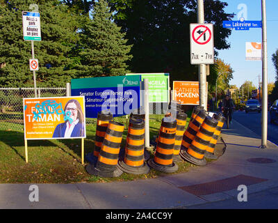 Bornes d'Orange, un arrêt de bus, les cyclistes et les affiches de la campagne électorale fédérale pour faire un coin occupé à Lakeview et Bronson, Ottawa, Ontario, Canada. Banque D'Images