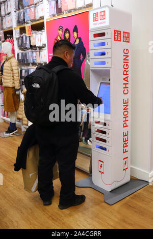 Une personne utilise un ChargeItSpot kiosque de charge de téléphone situé à l'intérieur d'un magasin de vente au détail Banque D'Images