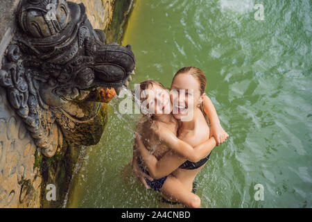 Mère et fils les voyageurs à hot springs banjar. L'eau thermale est sorti de la bouche de statues dans un hot springs de Banjar, Bali, Indonésie Banque D'Images