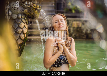 Jeune femme de hot springs banjar. L'eau thermale est sorti de la bouche de statues dans un hot springs de Banjar, Bali, Indonésie Banque D'Images