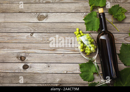 Bouteille de vin avec un verre et grappe de raisins sur une table en bois avec copie espace, vue du dessus Banque D'Images