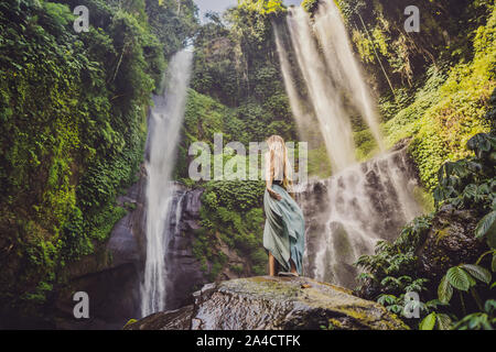 Femme en robe turquoise à l'Sekumpul cascades dans la jungle sur l'île de Bali, Indonésie. Concept de voyage Bali Banque D'Images