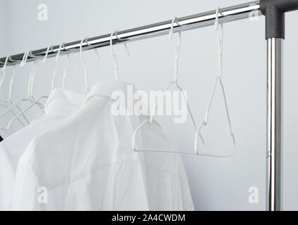 White men's shirts froissé accrochée à un cintre en métal, fond blanc Banque D'Images