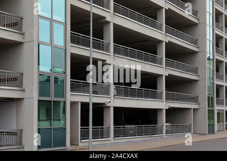 Parking voiture la façade de l'immeuble avec des murs de béton gris et les fenêtres de verre Banque D'Images