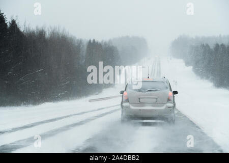 Il voiture roule sur une route d'hiver dans un blizzard Banque D'Images