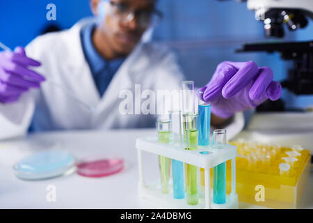 Close up of young man holding test tube afro-américaines tout en travaillant sur des échantillons en laboratoire de recherches médicales, copy space Banque D'Images