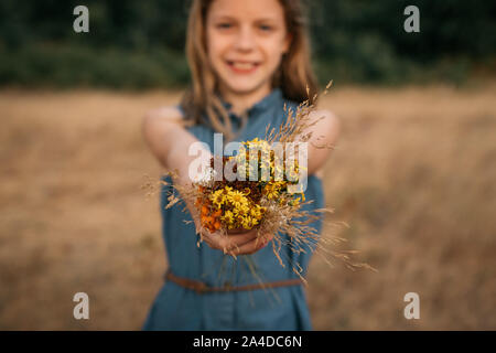 Smiling Girl standing in a field in un bouquet de fleurs sauvages, Pays-Bas Banque D'Images