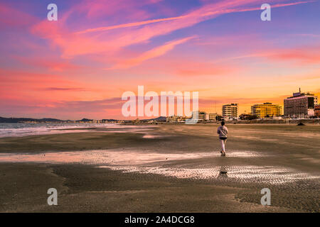 Femme marche sur la plage au coucher du soleil, Riccione, Rimini, Italie Banque D'Images