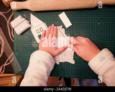 Girl making a maison blanche d'artisanat de Noël Banque D'Images