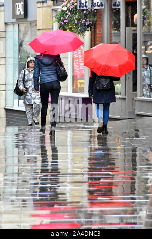Pluie deux femmes marchent par temps humide dans le centre-ville piétons seulement les acheteurs zone de rue dans la pluie sous le parapluie rouge et réflexions Durham Angleterre Royaume-Uni Banque D'Images