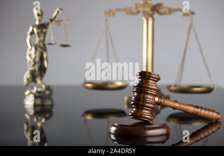 Concept de la Justice. Statue de Themis, l'échelle et judge's gavel sur la table en verre et le fond gris. Banque D'Images