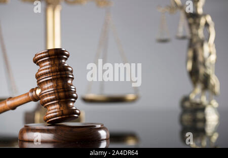 Concept de la Justice. Statue de Themis, l'échelle et judge's gavel sur la table en verre et le fond gris. Banque D'Images