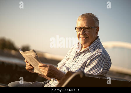 Outdoor portrait of senior man qui est la lecture de journaux. Banque D'Images