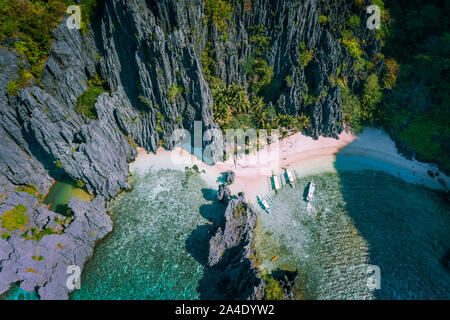 El Nido, Palawan, Philippines. Vue aérienne de secret caché Lagoon beach avec des bateaux touristiques sur island hopping tour entourée de falaises karstiques Banque D'Images