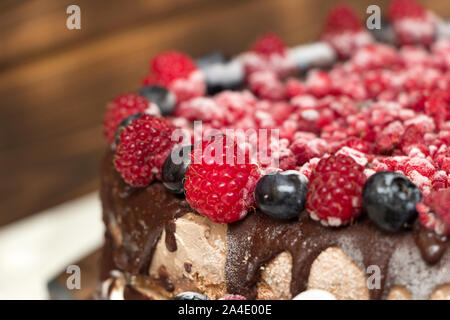 Une vue rapprochée de gâteau au chocolat végétalien couverts avec les framboises et les bleuets, congelés dans le réfrigérateur, sur une table avec arrière-plan flou. Copie Banque D'Images