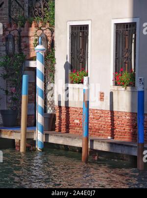 Les poteaux d'amarrage bleu et blanc pour les gondoles et les petits bateaux à Venise en Italie. Banque D'Images