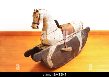 Cheval à bascule en bois historique debout sur un plancher en bois de couleur dorée devant un mur blanc, rétro arrière with copy space Banque D'Images