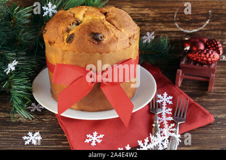 Panettone traditionnel cake aux fruits secs sur la table en bois avec décoration de Noël. Pain sucré italien avec ruban rouge et bow pour célébrer Banque D'Images