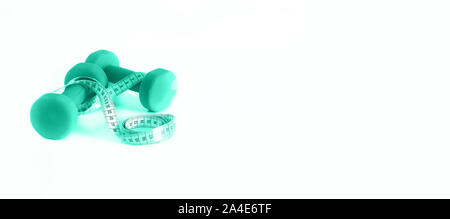 Concept de remise en forme. Les haltères et un ruban à mesurer en arrière-plan couleur menthe. Couleur turquoise et vert à la mode. Copyspace. Banque D'Images