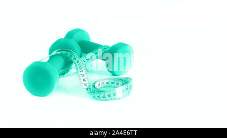 Concept de remise en forme. Les haltères et un ruban à mesurer en arrière-plan couleur menthe. Couleur turquoise et vert à la mode. Copyspace. Banque D'Images