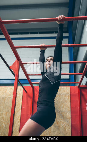 Grande sportive exerçant sur les barres de singe Banque D'Images