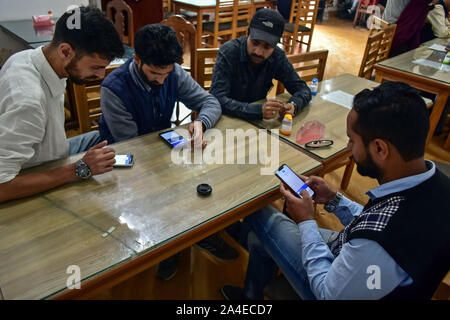 Les hommes regardent leur téléphone mobile après la communication en cours de restauration en cachemire.Des services de téléphonie mobile ont été restaurés sur le réseau BSNL dans la vallée du Cachemire après plus de 72 jours de la verrouiller au Jammu-et-Cachemire. Banque D'Images