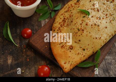 - CheesePizza italien Calzone repliée sur fond de bois rustique Banque D'Images