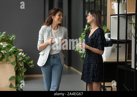 L'origine ethnique asiatique et caucasienne collègues femmes bavardant dans office hallway Banque D'Images