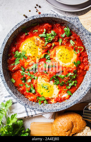 Shakshuka traditionnels dans une casserole. Oeufs frits à la sauce tomate aux herbes. Banque D'Images