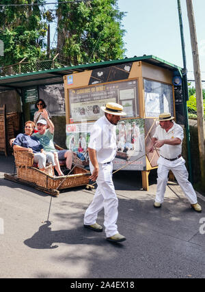 Monte, Madeira, Portugal - Sep 14, 2019 : panier en osier traîneaux pilotes, Carreiros do Monte, conduisant des personnes en descente. Moyen de transport historique, maintenant une attraction touristique. Chapeau de paille typique. Banque D'Images