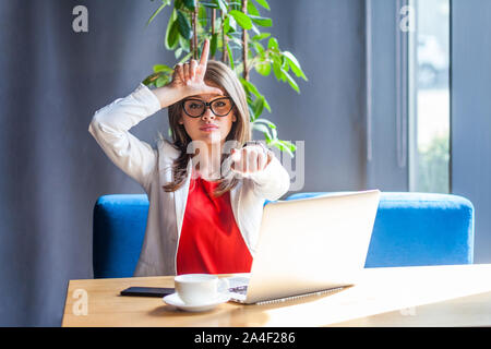 Vous êtes perdant ! Portrait de grave belle brunette élégante jeune femme assise avec verres en perdant le geste, en soulignant et en regardant la caméra. indoo Banque D'Images