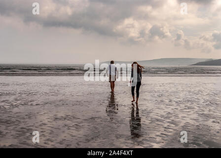 Couple en train de marcher sur une plage de sable en laissant des traces de pas dans le sable. Un père et sa fille profiter de la journée. Jour nuageux. Banque D'Images