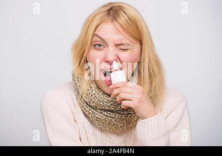 Le nettoyage. Femme malade médicament pulvérisation dans le nez. Mauvaise fille avec le nez à l'aide de spray nasal. Cute femme froide ou une allergie nasale de soins infirmiers. Le traitement de rhume ou de rhinite allergique. Banque D'Images