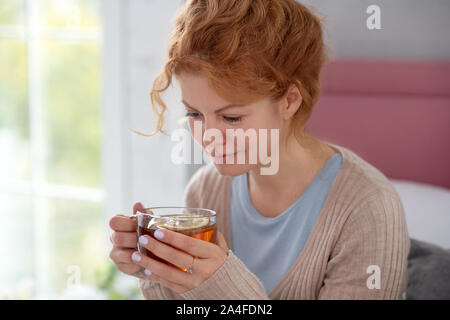 Curly femme malade de se sentir bien tout en buvant du thé chaud Banque D'Images