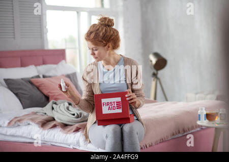 Femme à la pulvérisation à après avoir sortie à partir de la trousse de premiers soins Banque D'Images