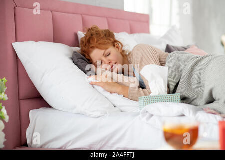 Curly red-haired woman sleeping après la prise de comprimés Banque D'Images