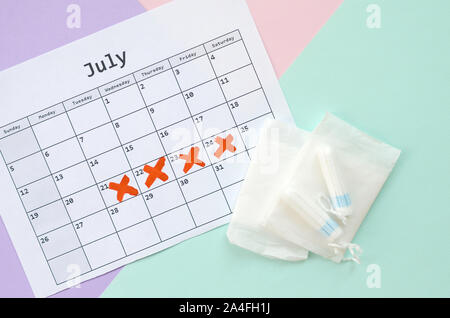 Télévision avec calendrier et composition des tampons menstruels et packs pad bleu sur fond pastel rose et lilas. Concept de gynécologie. Jours critiques pms Banque D'Images