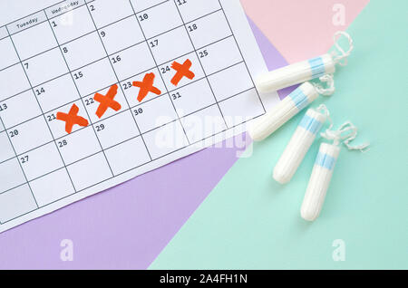 Télévision avec calendrier et composition des tampons menstruels sur rose et lilas bleu pastel arrière-plan. Concept de gynécologie. Jours critiques pms objets d'époque Banque D'Images