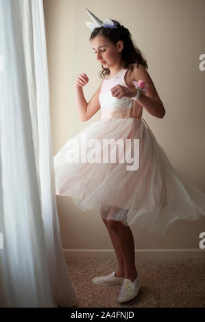 Fille de 10 à 12 ans faisant tournoyer par fenêtre habillé en robe rose fantaisie Banque D'Images