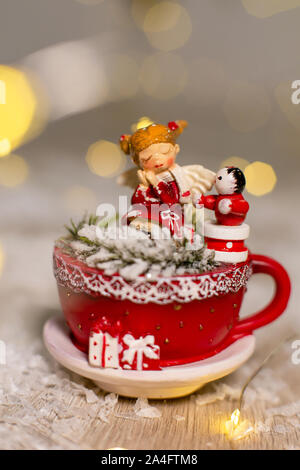 Décoration pour les vacances de Noël. Ambiance chaleureuse atmosphère confortable. Statuette de une tasse rouge dans lequel un bonhomme et un petit homme assis Banque D'Images